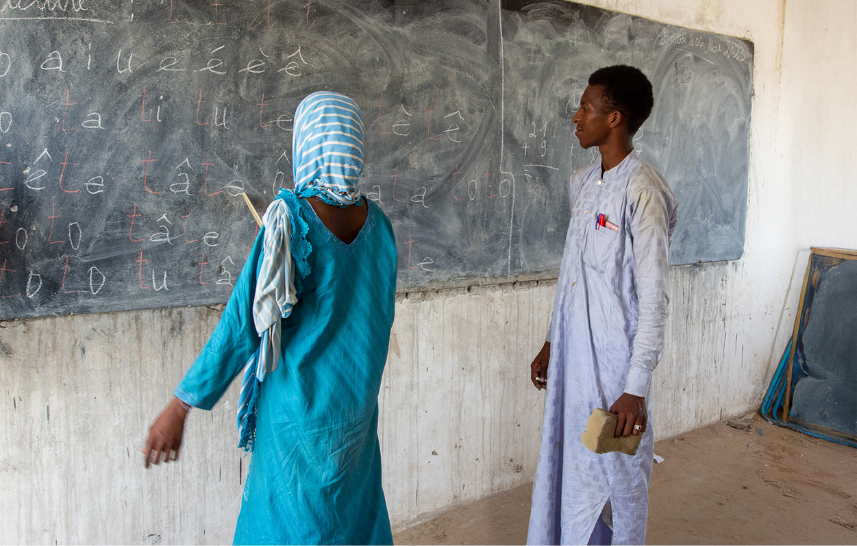 Teacher and student in front of a blackboard in a classroom