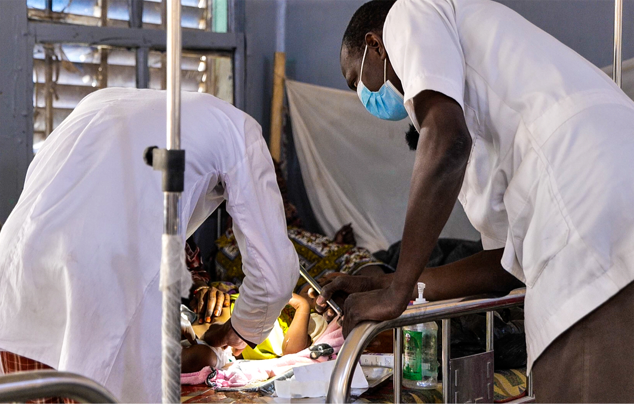 Caregivers examining a young child in a hospital bed